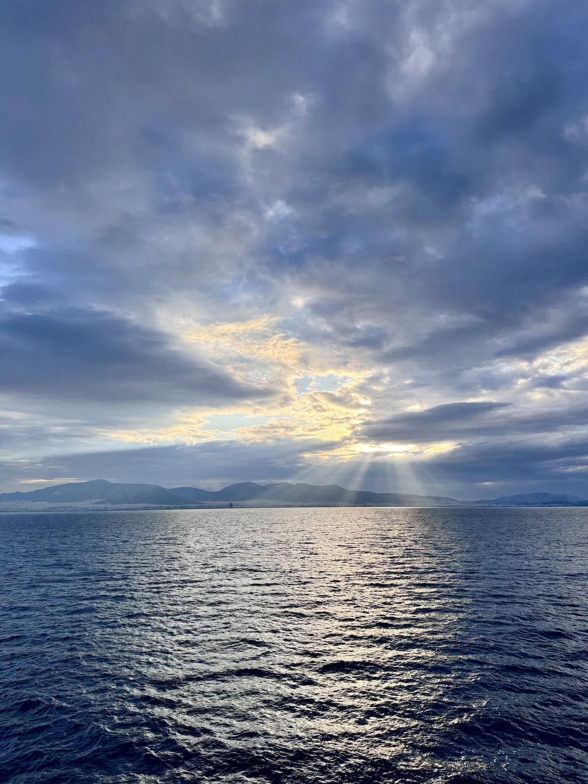 Sun setting over ocean with islands in the distance.
