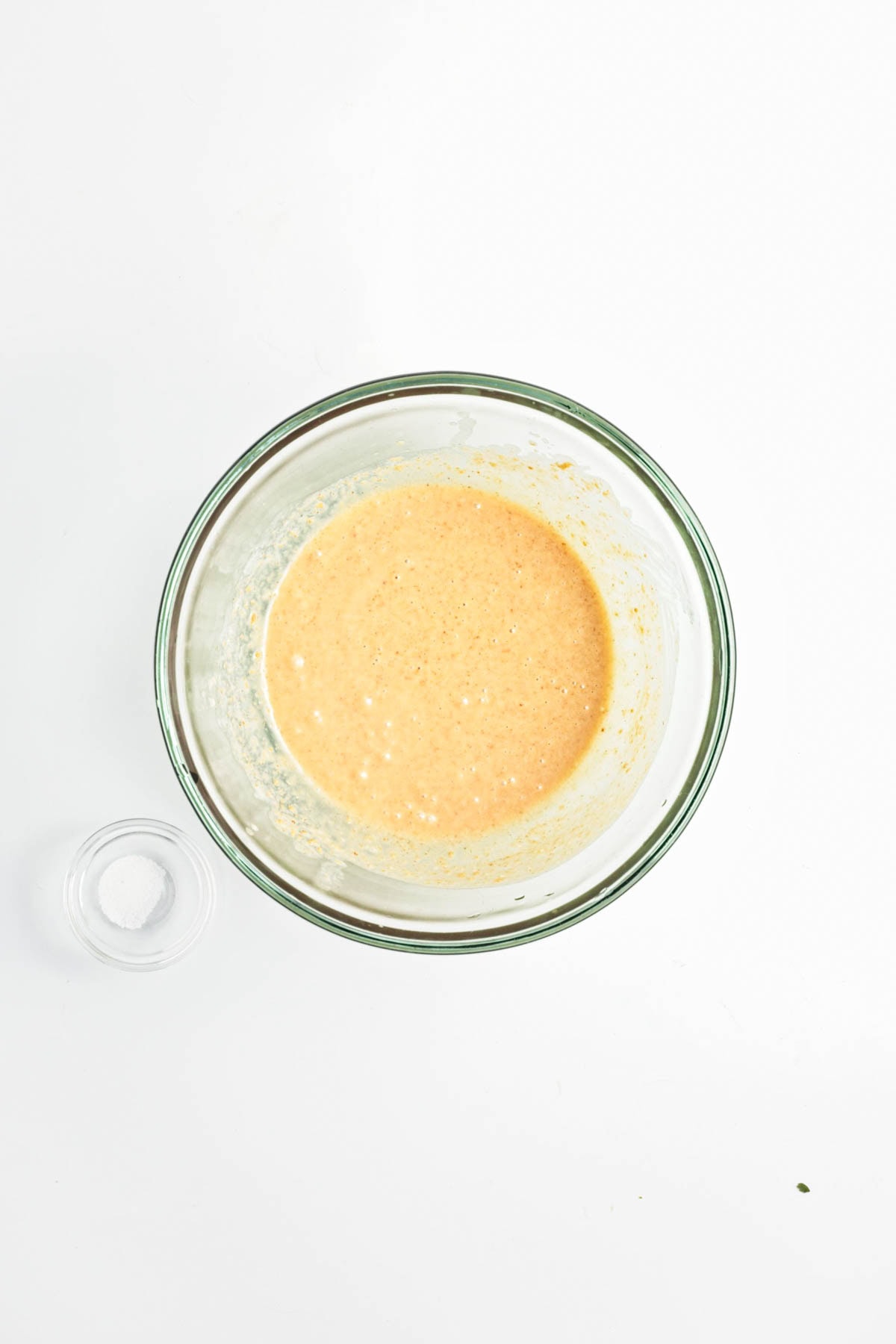 Peanut sauce in a glass bowl with smal empty glass bowl on side.