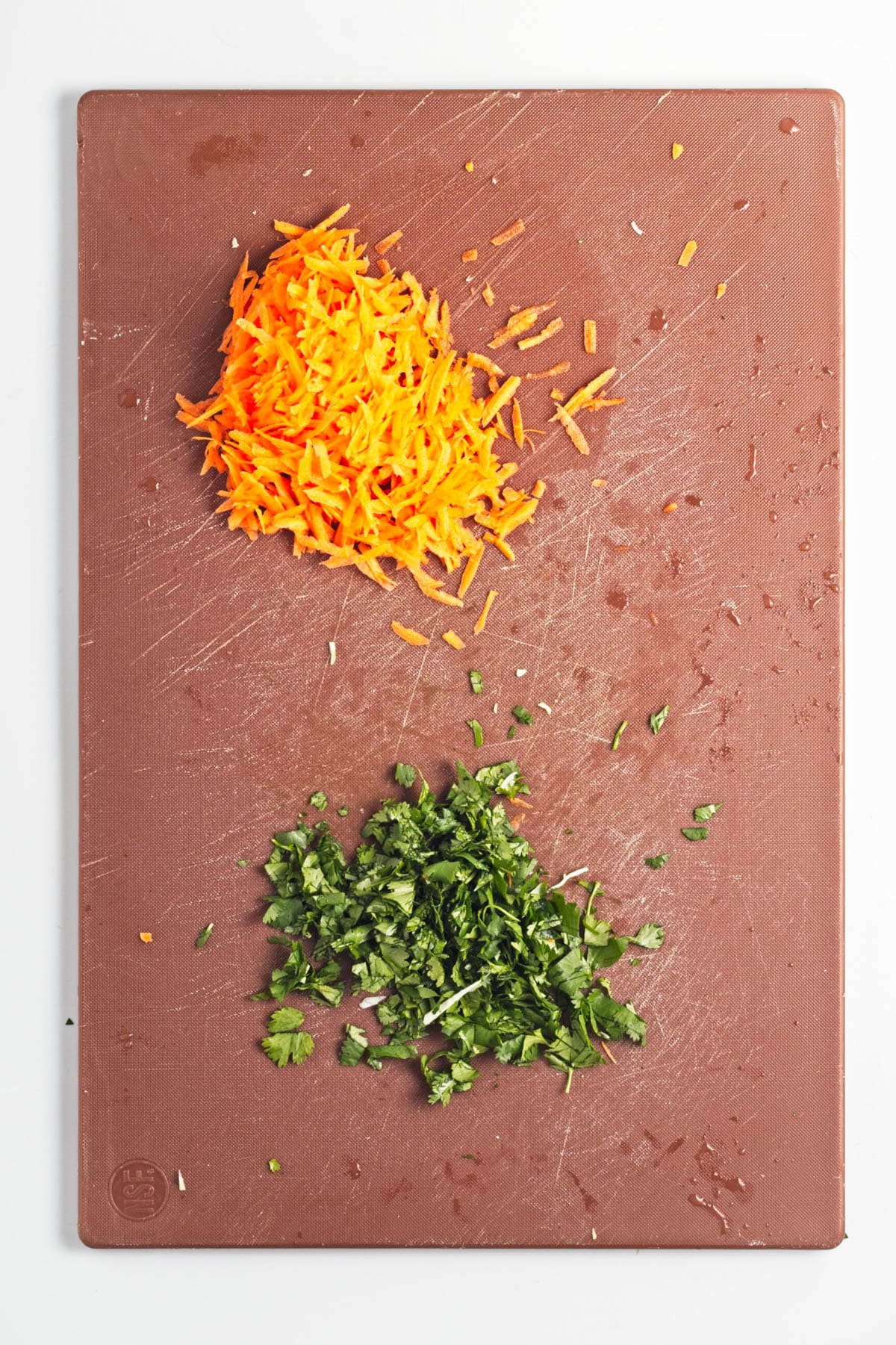 Shreded carrots and chopped cilantro on a cutting board.