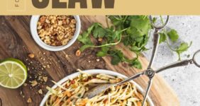 White bowl with shredded cabbage with cilantro and peanuts on wood board.