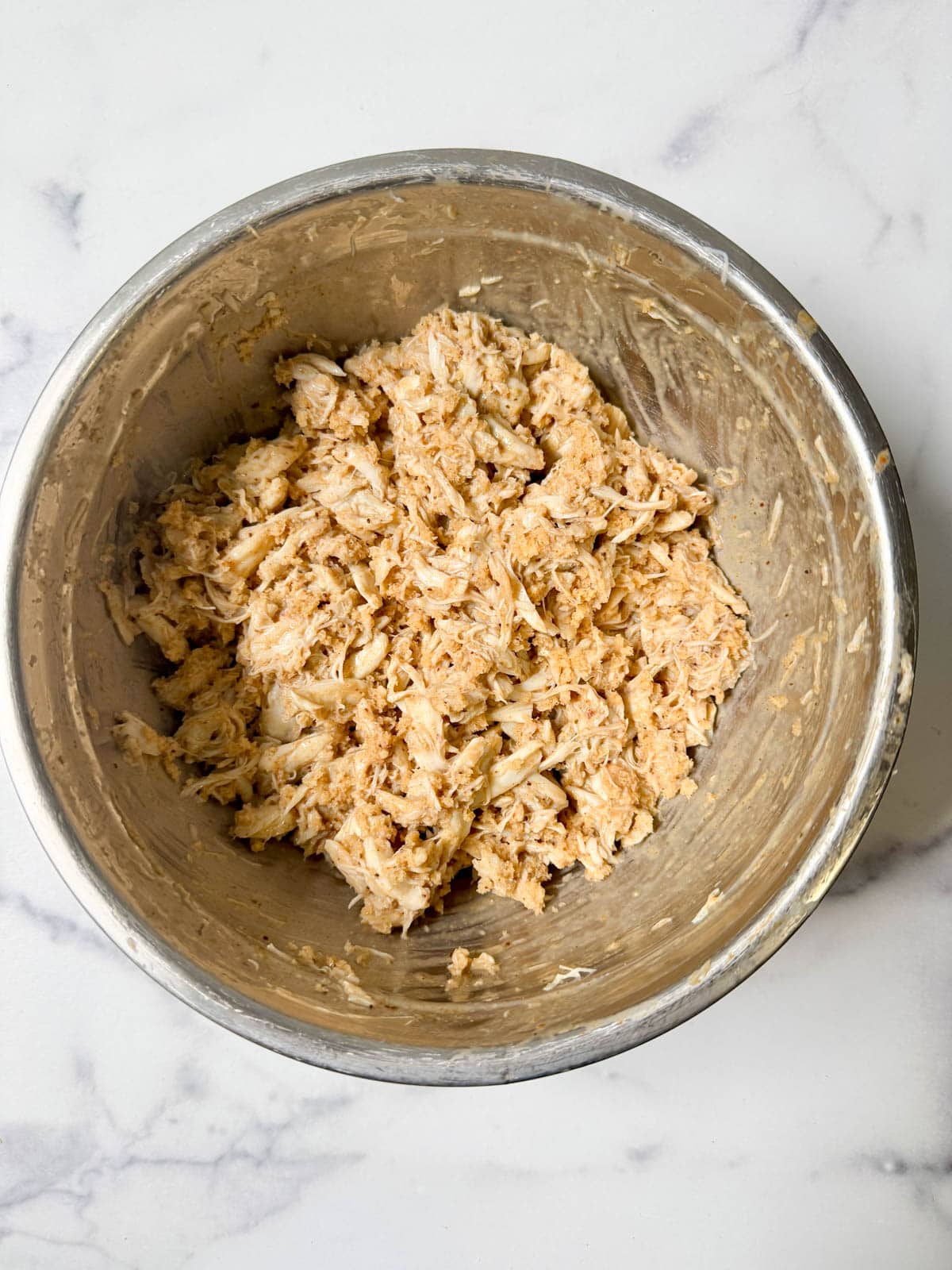 Crab cake mixture in a silver bowl.