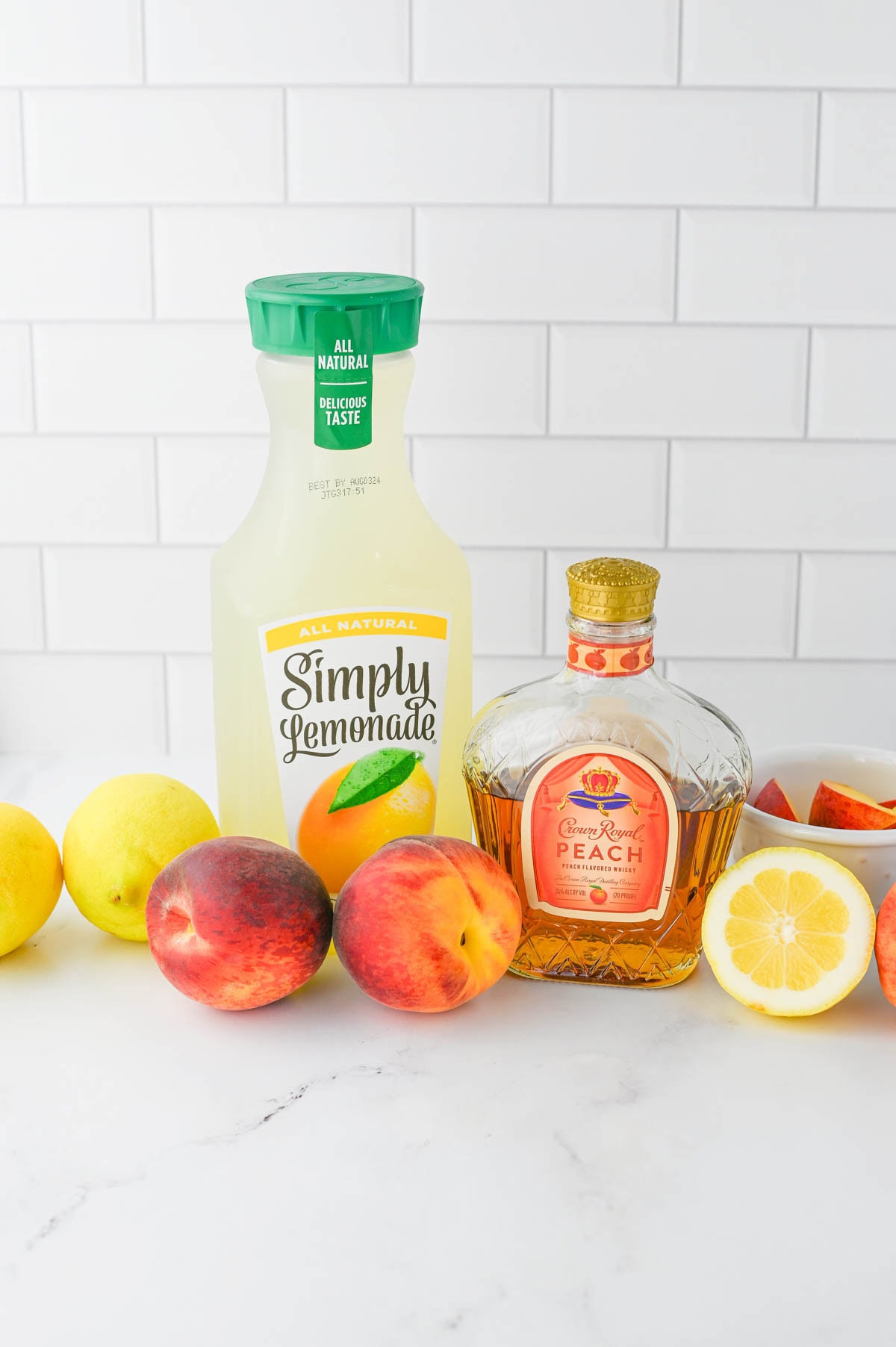 Bottle of lemonade, bottle of Crown Royal, peaches, and lemons.