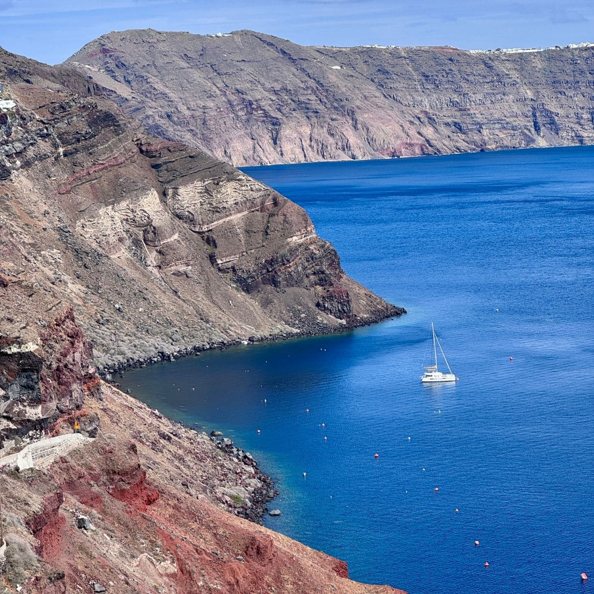 Mountains, blue sky, and blue sea with one white boat.