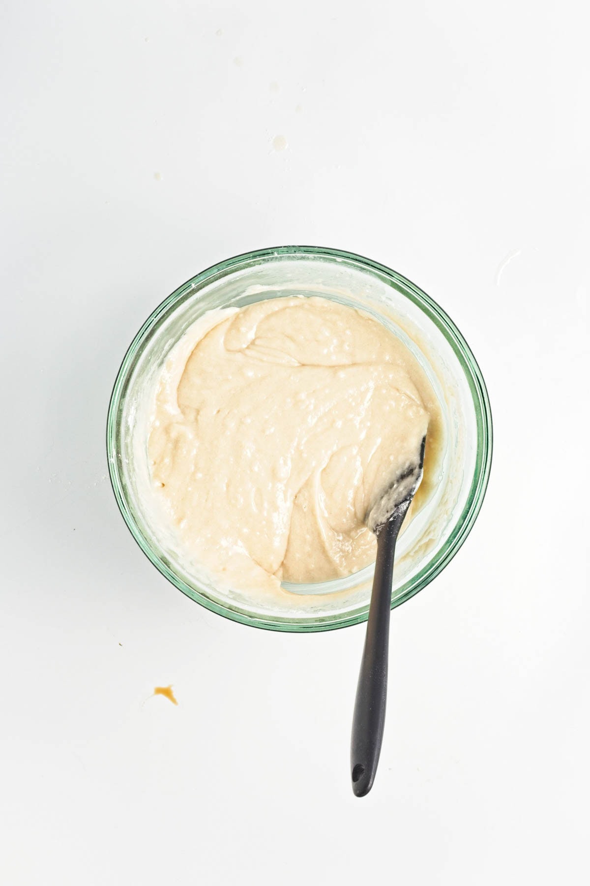 Cake batter in glass bowl on white counter.