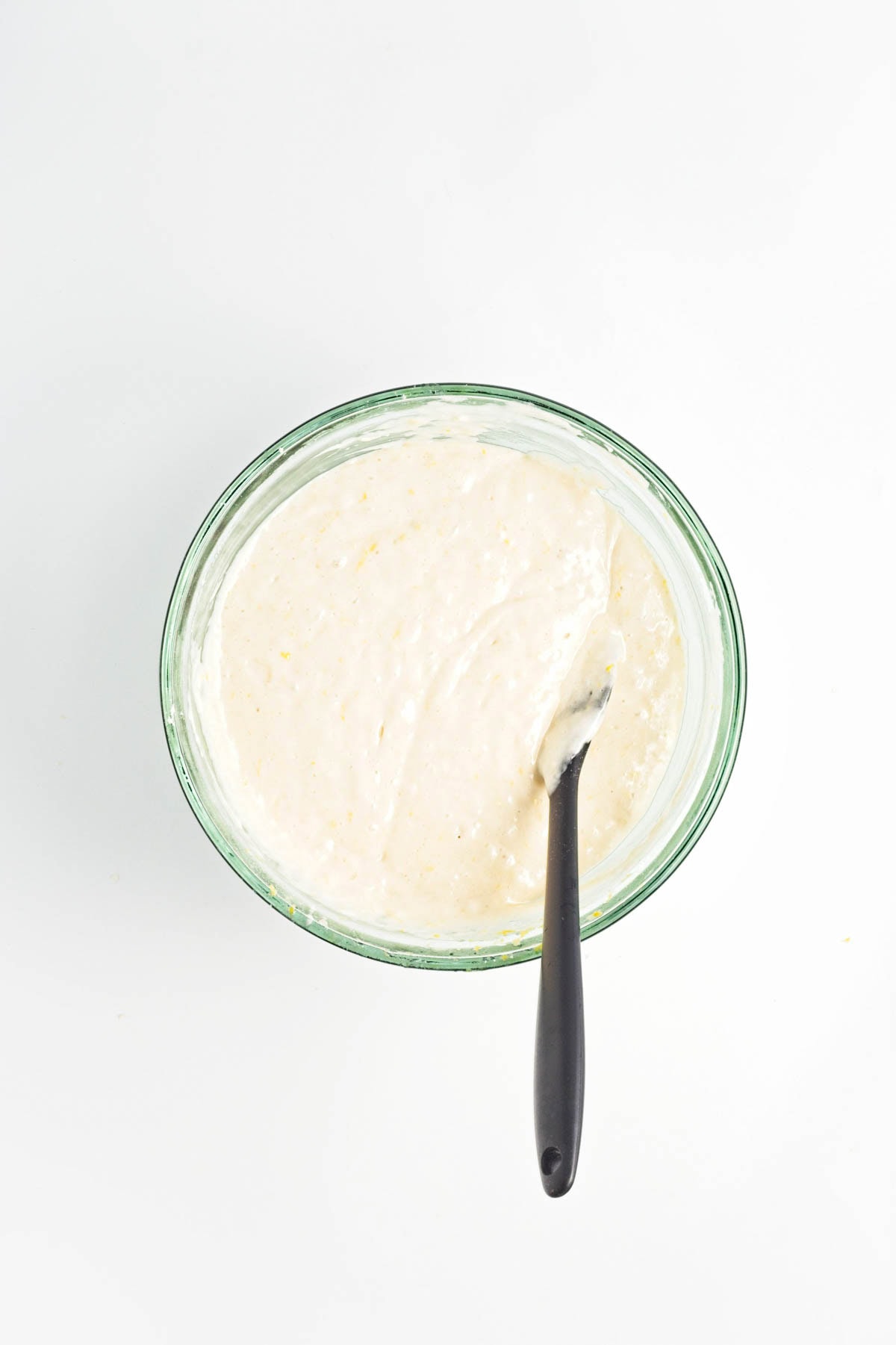 Icing in glass bowl with spatula.