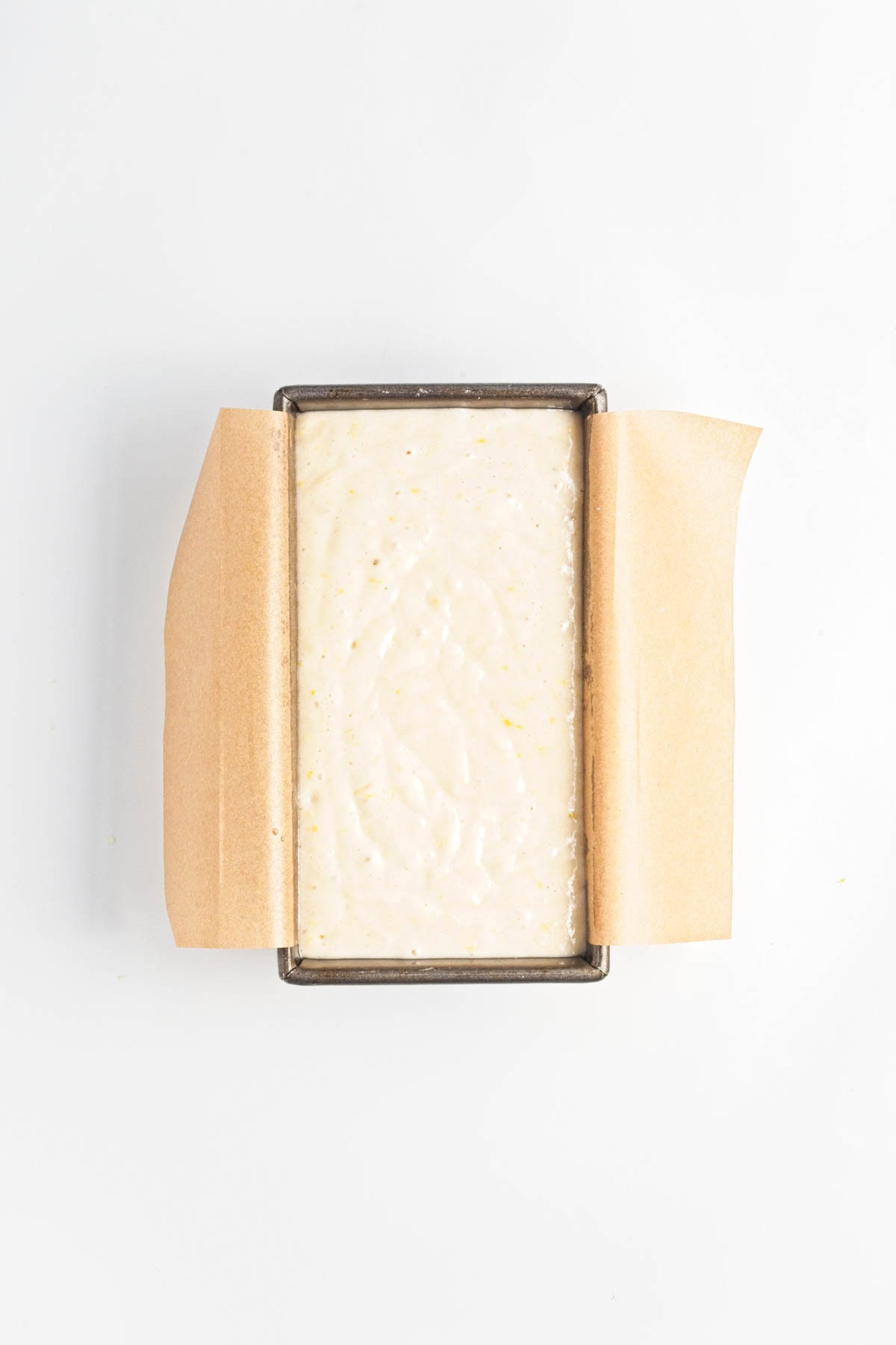 Cake batter in loaf pan over parchment paper.