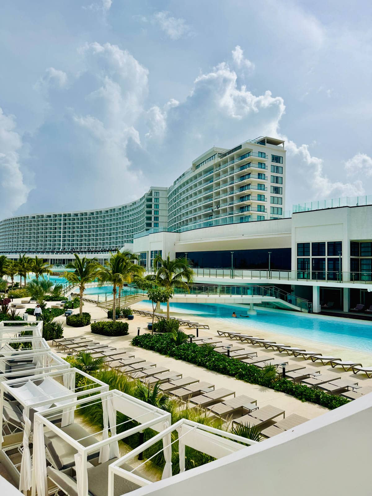 Hotel with swimming pool in front and longe chairs in front of pool.