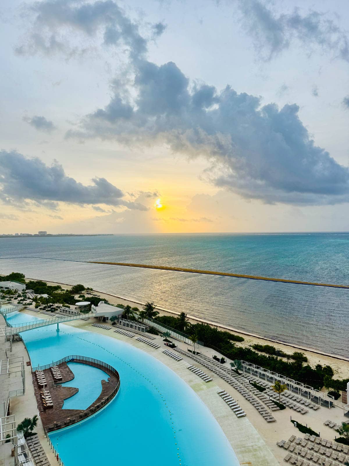 Sunrise over pool and beach at a resort.