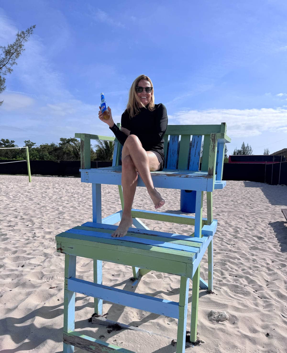 Woman in lifeguard chair holding a beer.