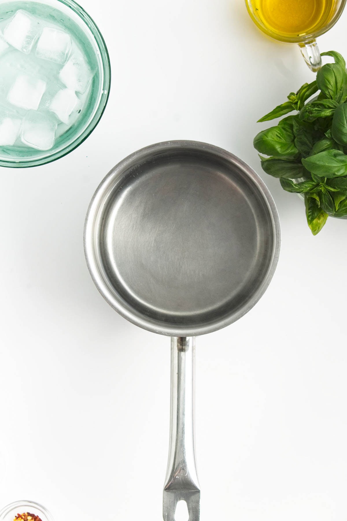 sauce pan with basil, olive oil, and bowl of ice to the side.