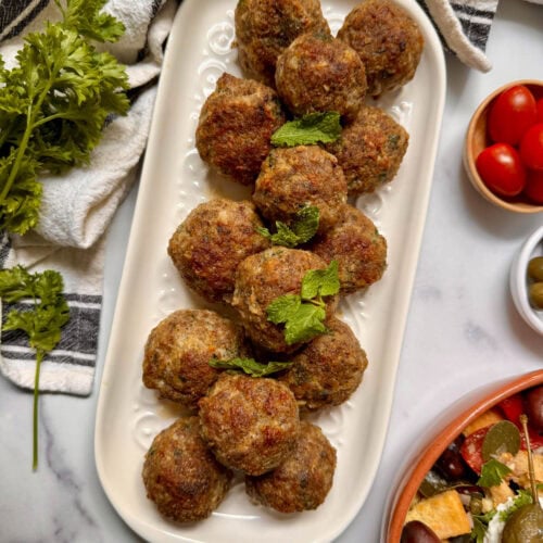 Meatballs on a platter surrounded by platters of other foods.