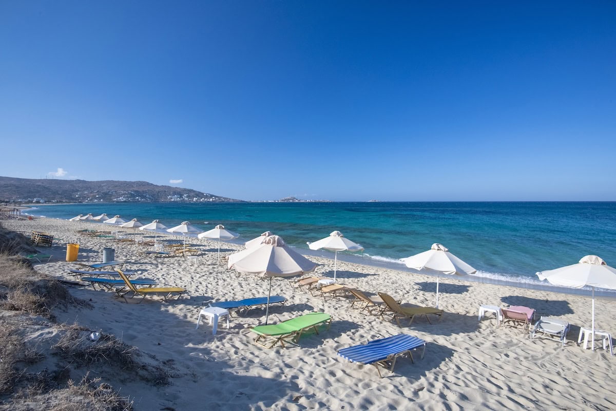 Beach with white umbrellas and lounge chairs along the water.