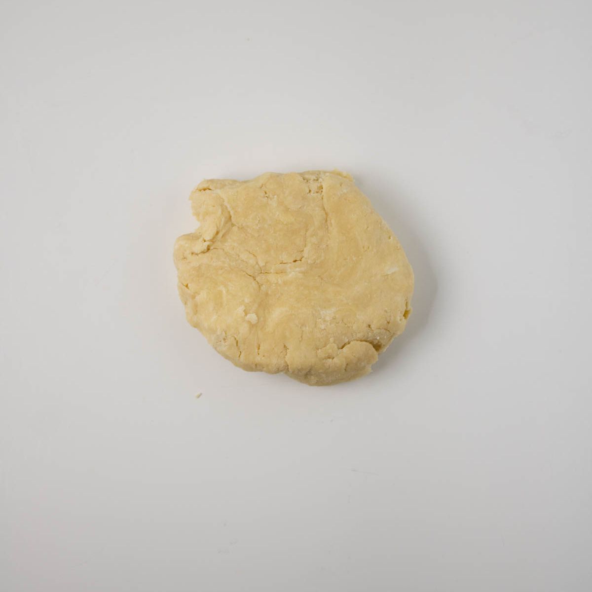 Round disc of dough on white counter.