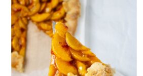 Peach galette with slice held up on spatula and rest of pie below.