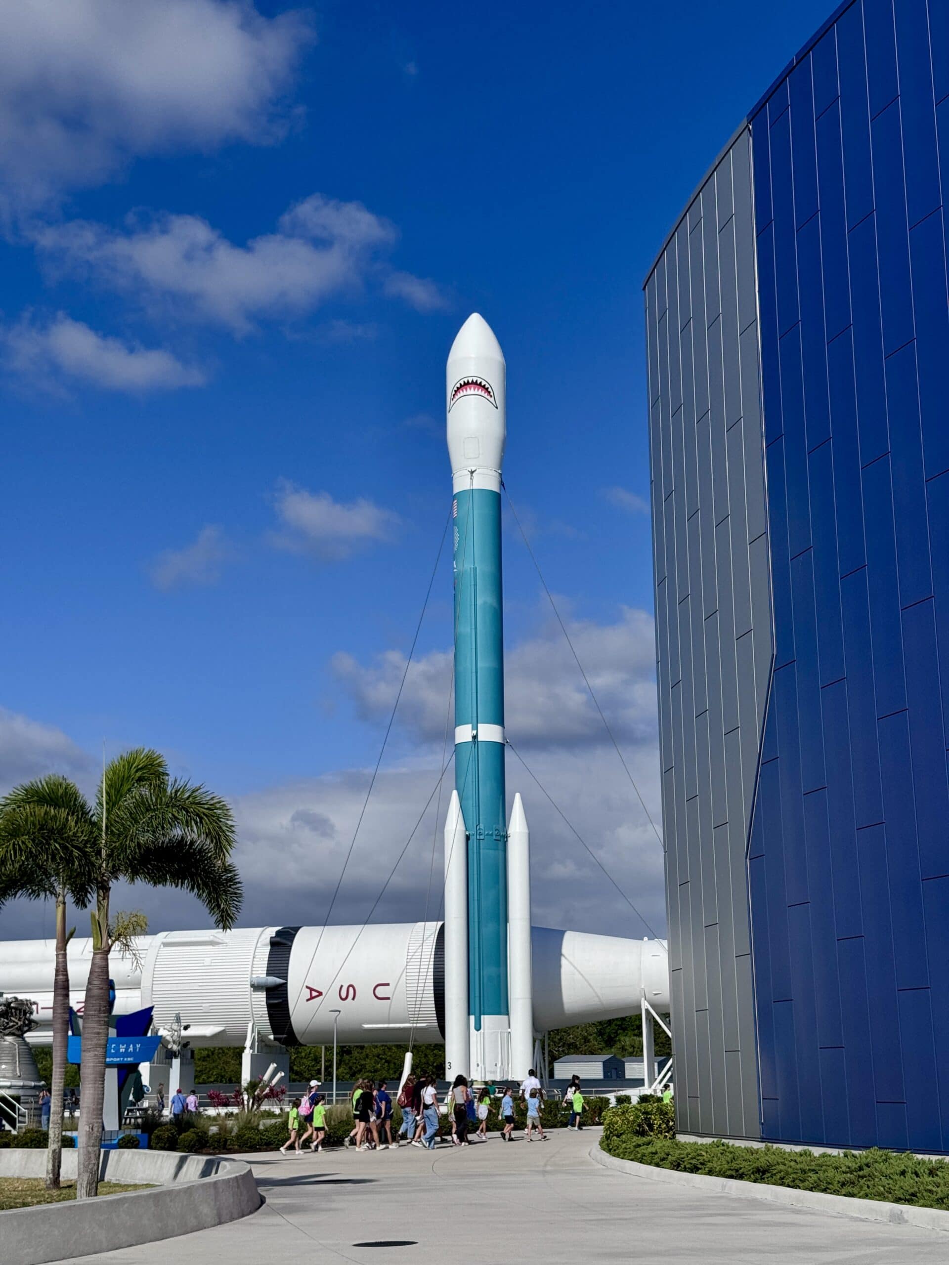 Rocket with a shark mouth against a blue sky with another rocket behind it.