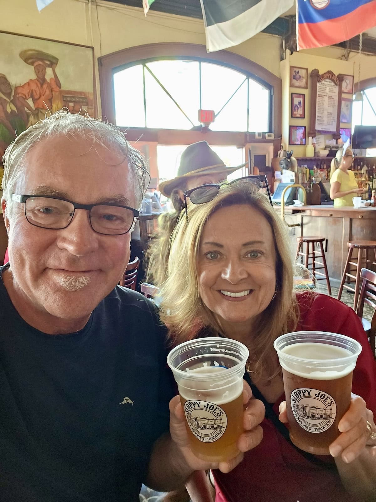 Man and woman holding up beers that say Sloppy Joe's in Key West, Florida.