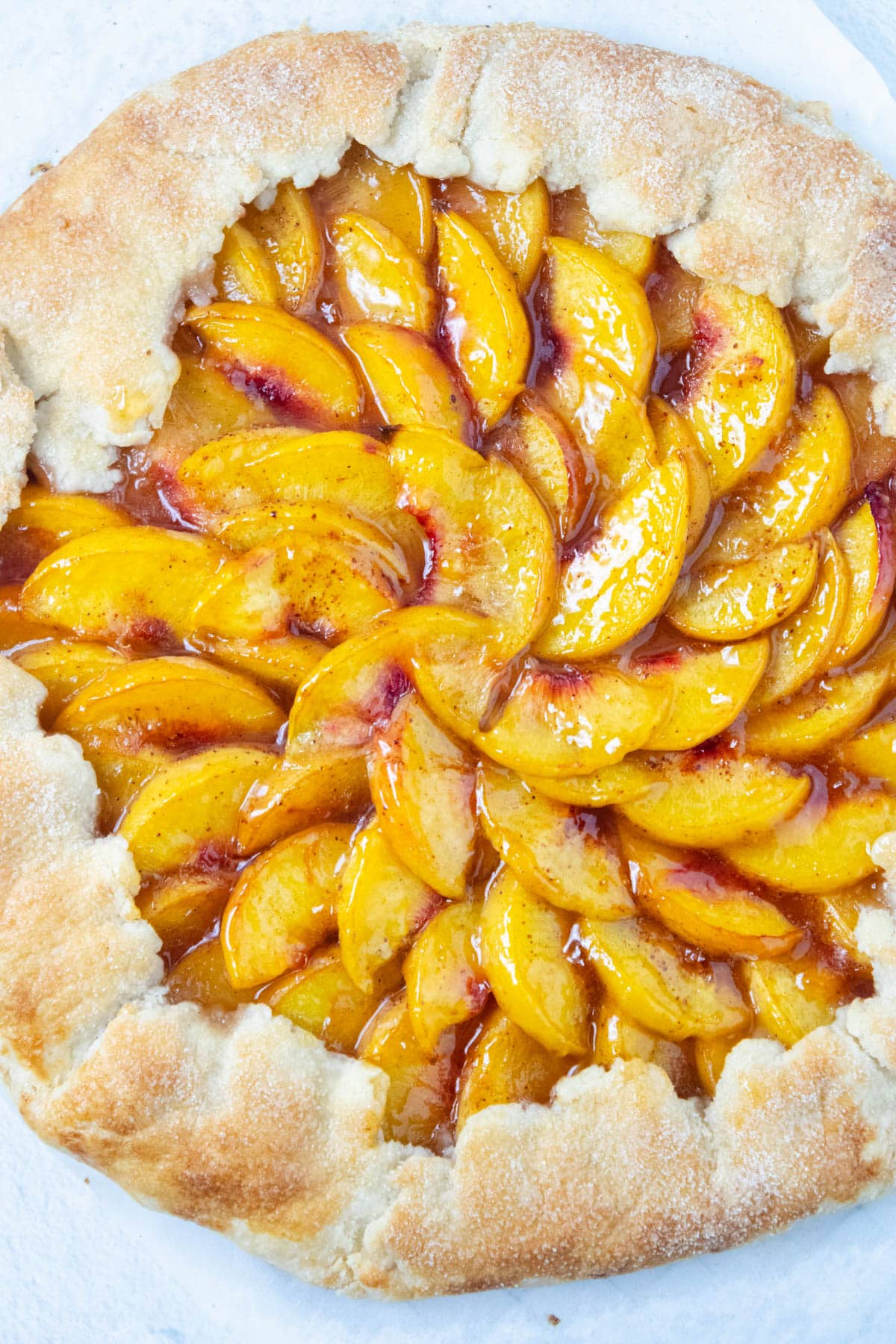 Baked peach galette on parchment paper.