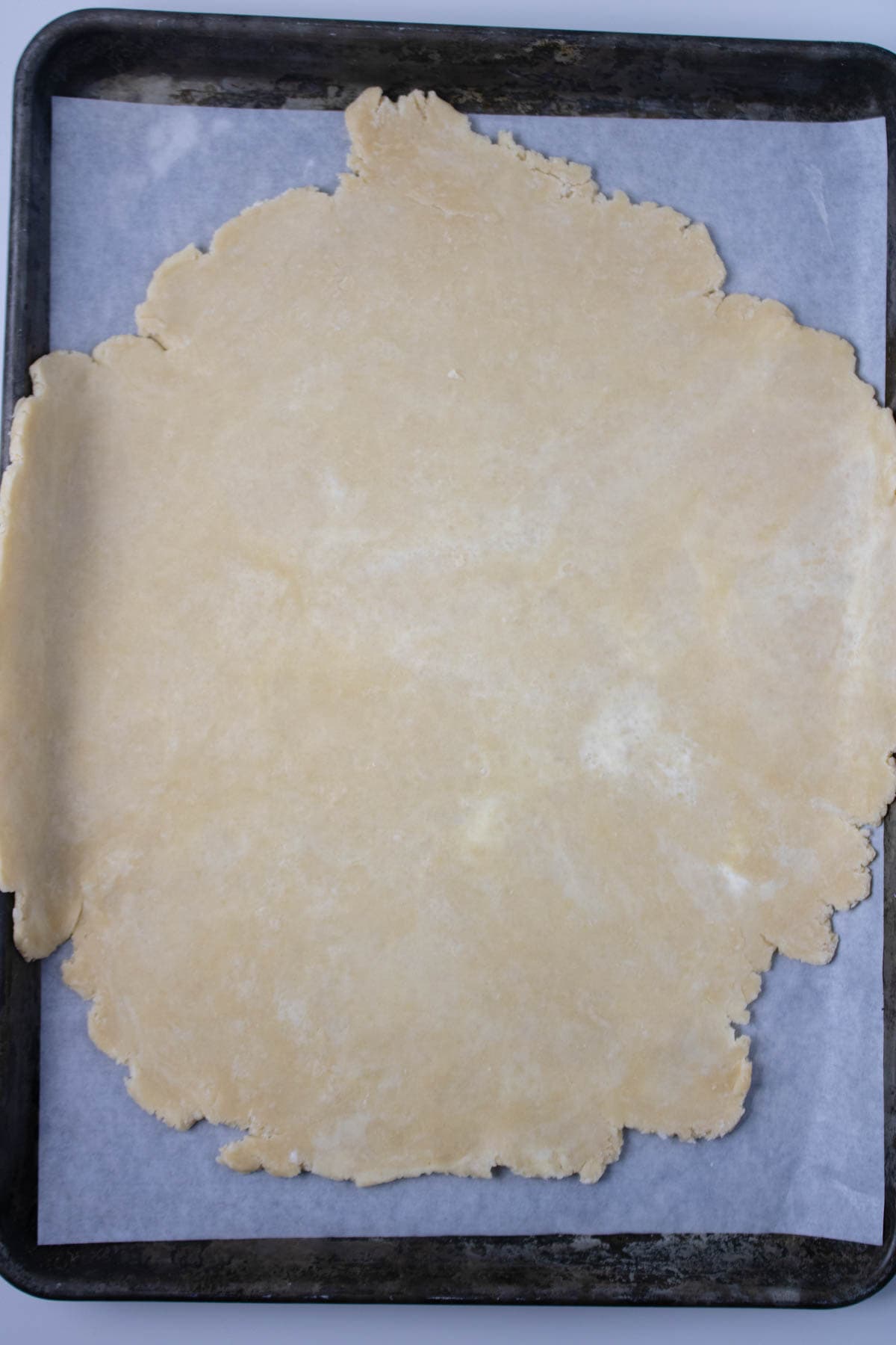 Pie crust rolled out and set on parchment paper on baking sheet.
