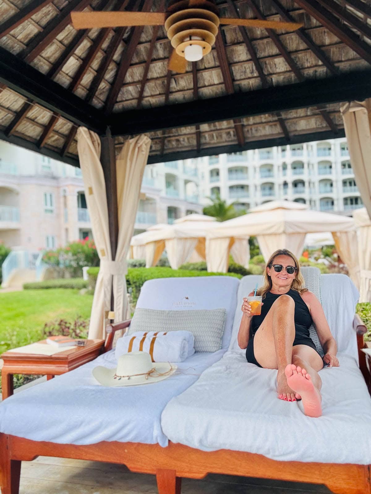 Woman sitting on lounge chair in cabana at resort.