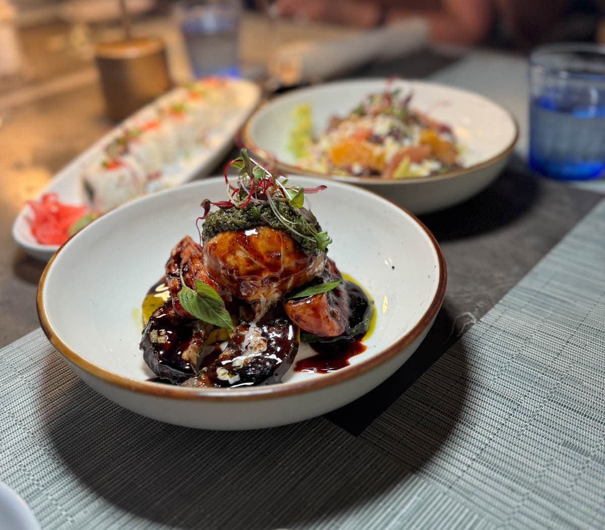 Salad with burrata and beets in bowl with other food in background.