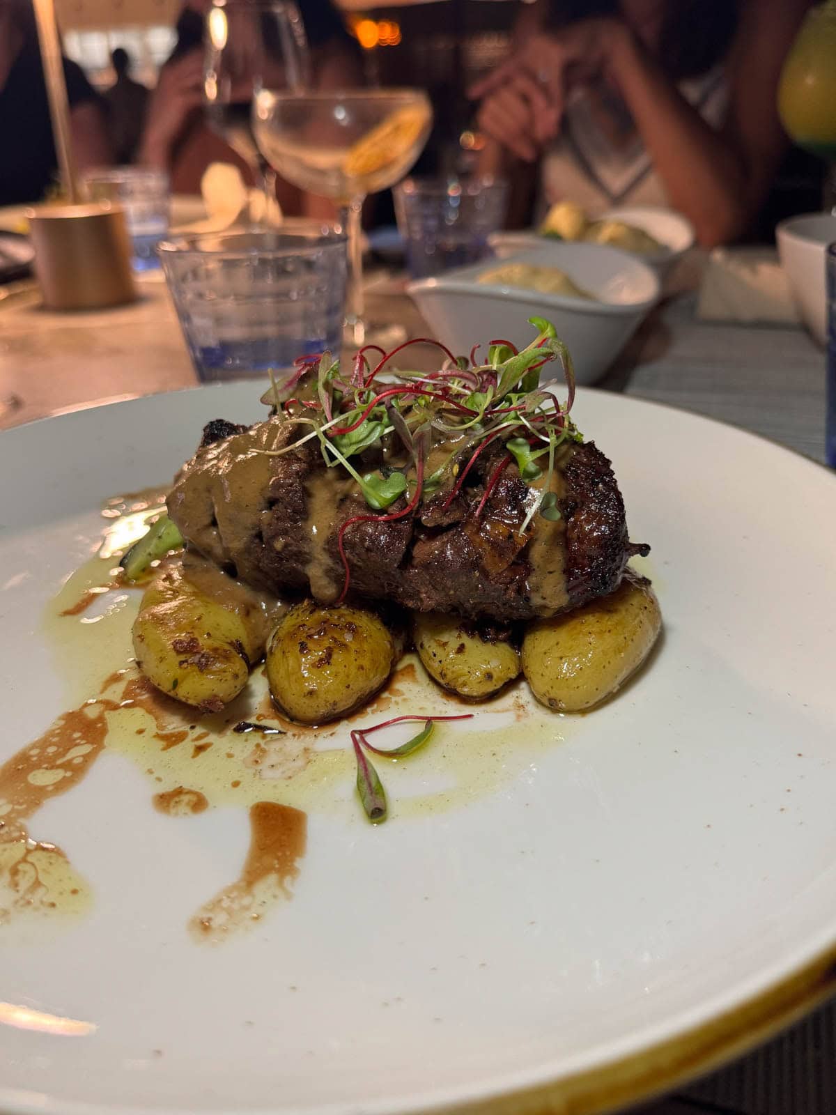Steak over potatoes with microgreens on top.