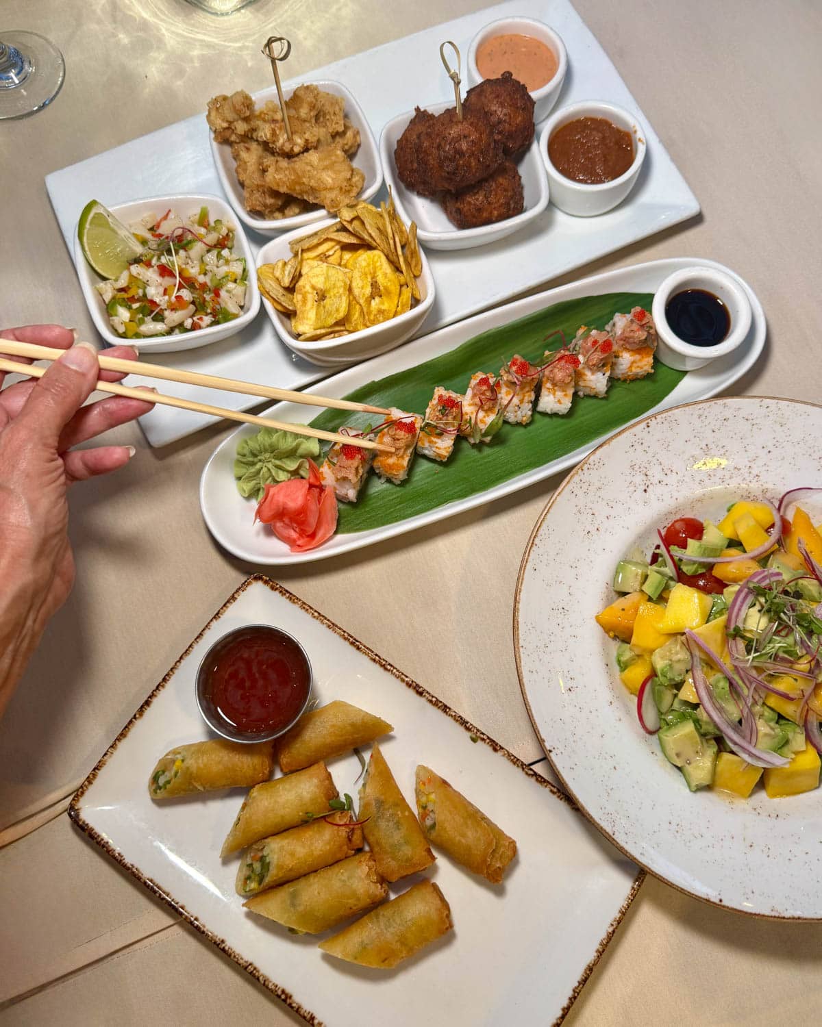 Sushi and other appetizers on a beige tablecloth.