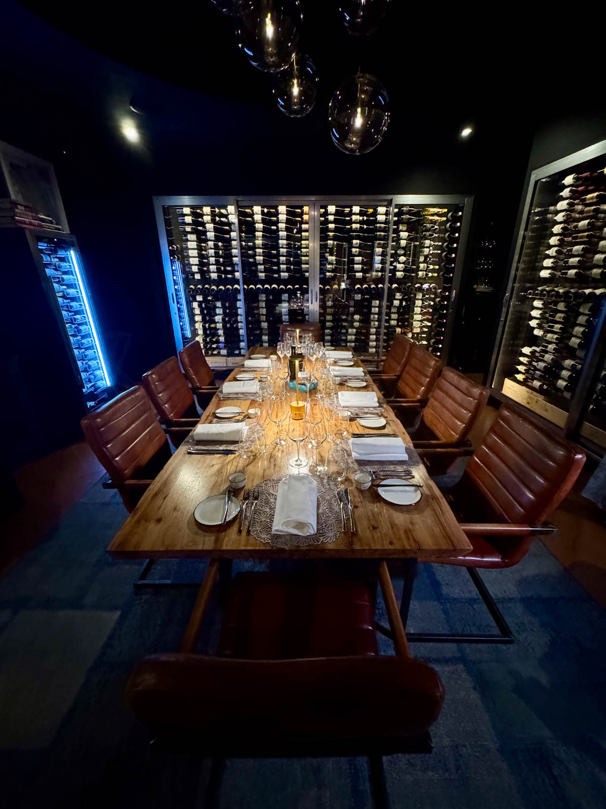 Dining room with table set and wine refrigerators in background.
