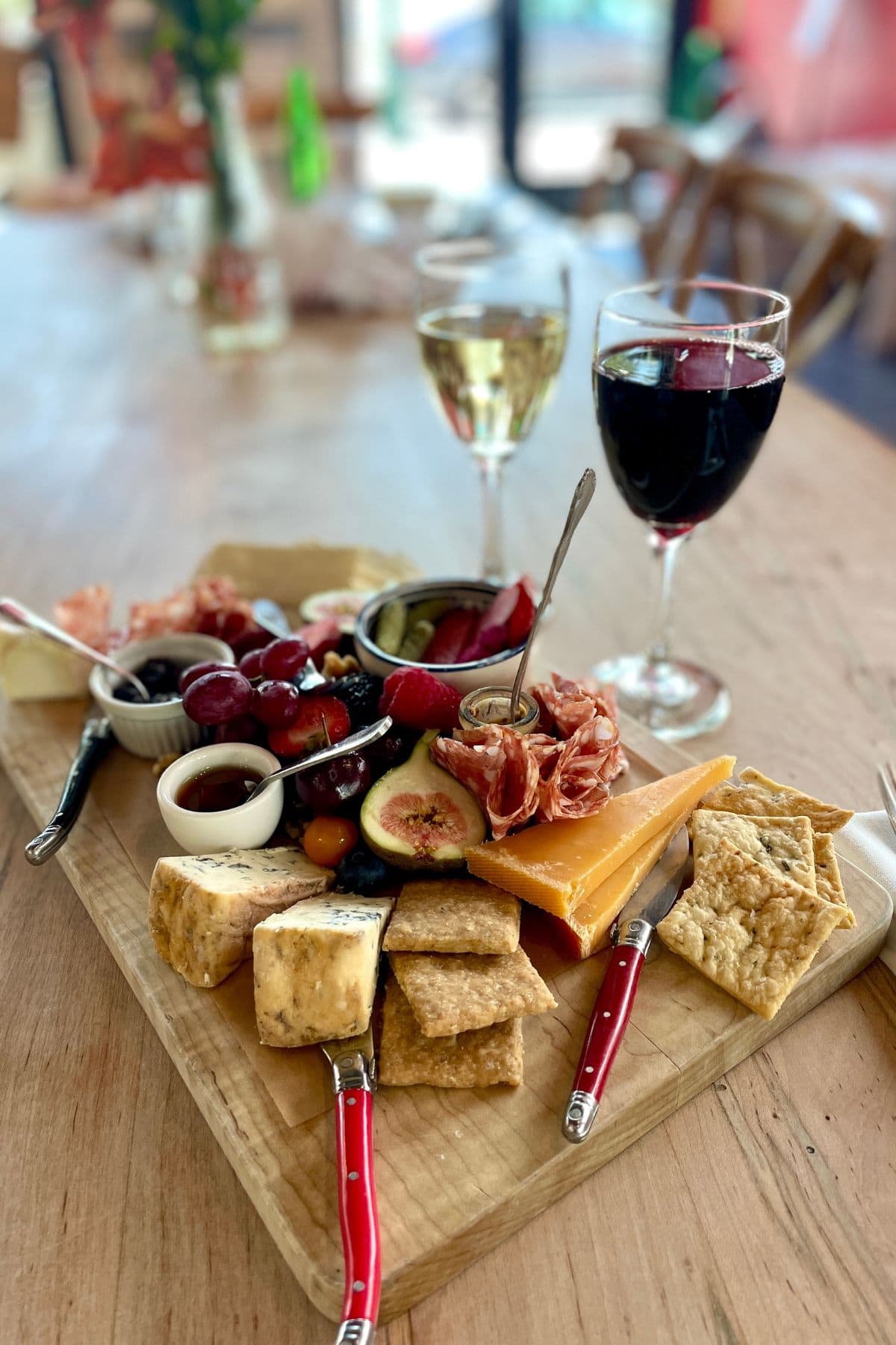 Charcuterie board with 2 glasses of wine in the background.