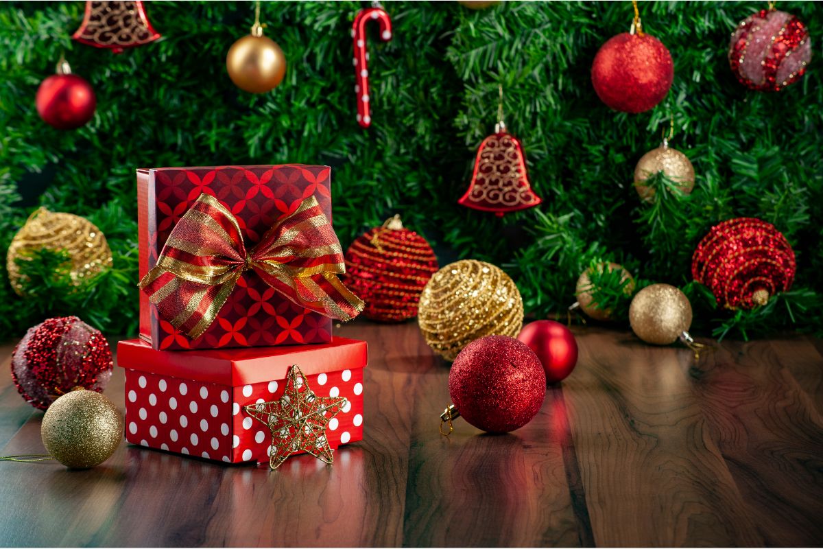 Gifts wrapped in red paper with Christmas tree and ornaments in background.