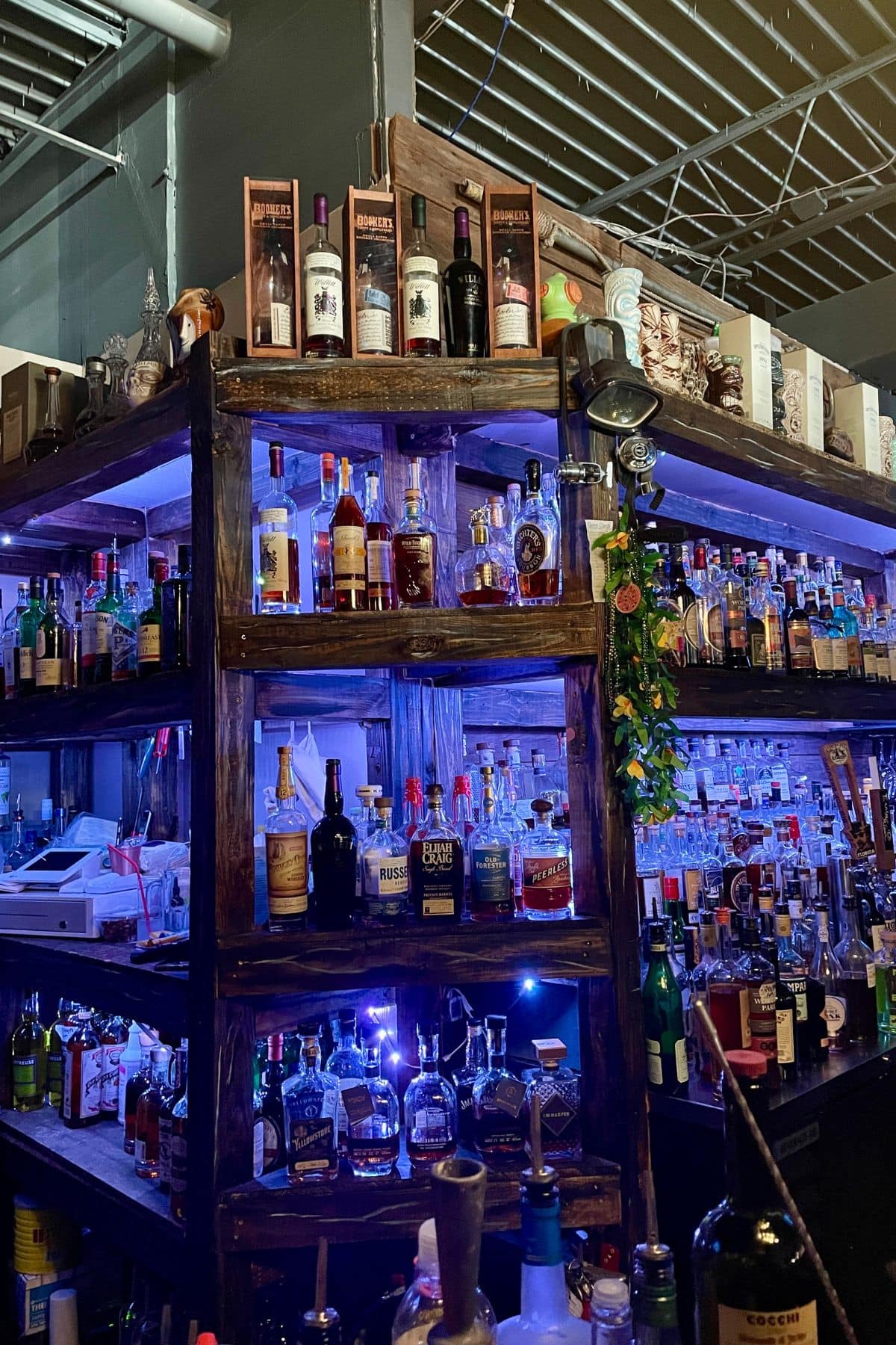 Bar shelves of bottles of liquor with black lights in the background.