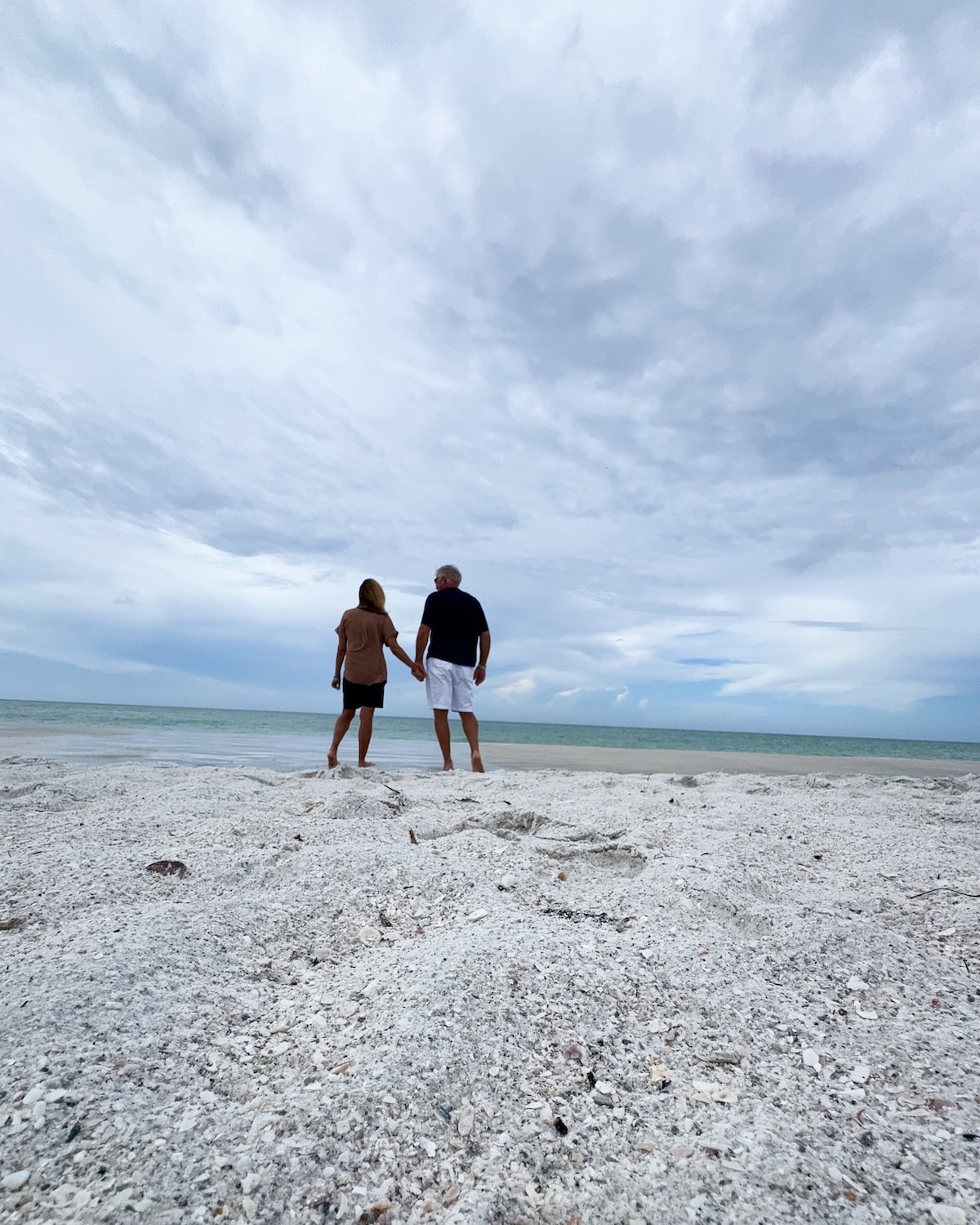 Man and woman holding hands at the beach.