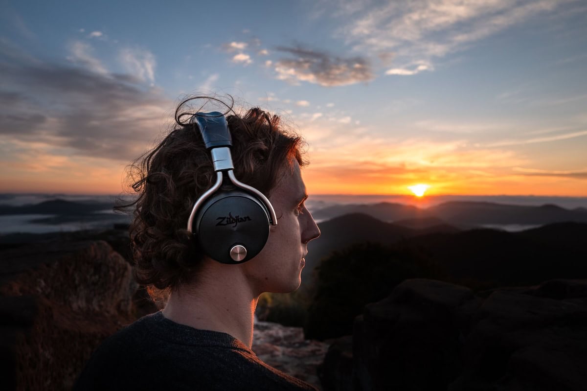 Man with headphones on and sunset in background.