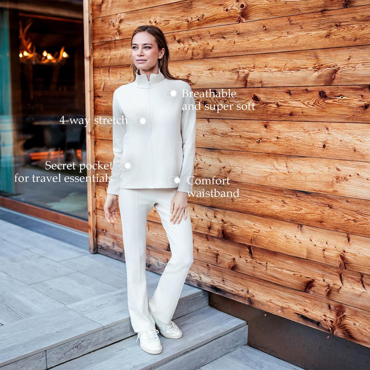 Woman in matching pants and jacket in front of wood wall.