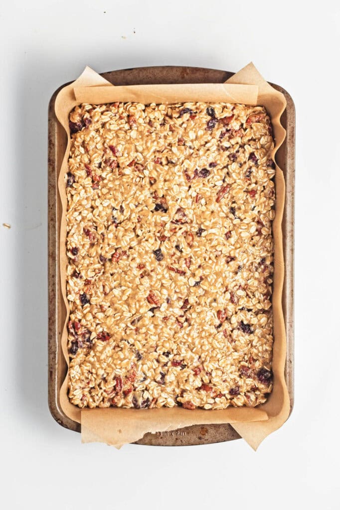 Unbaked oatmeal bars on parchment in baking pan.