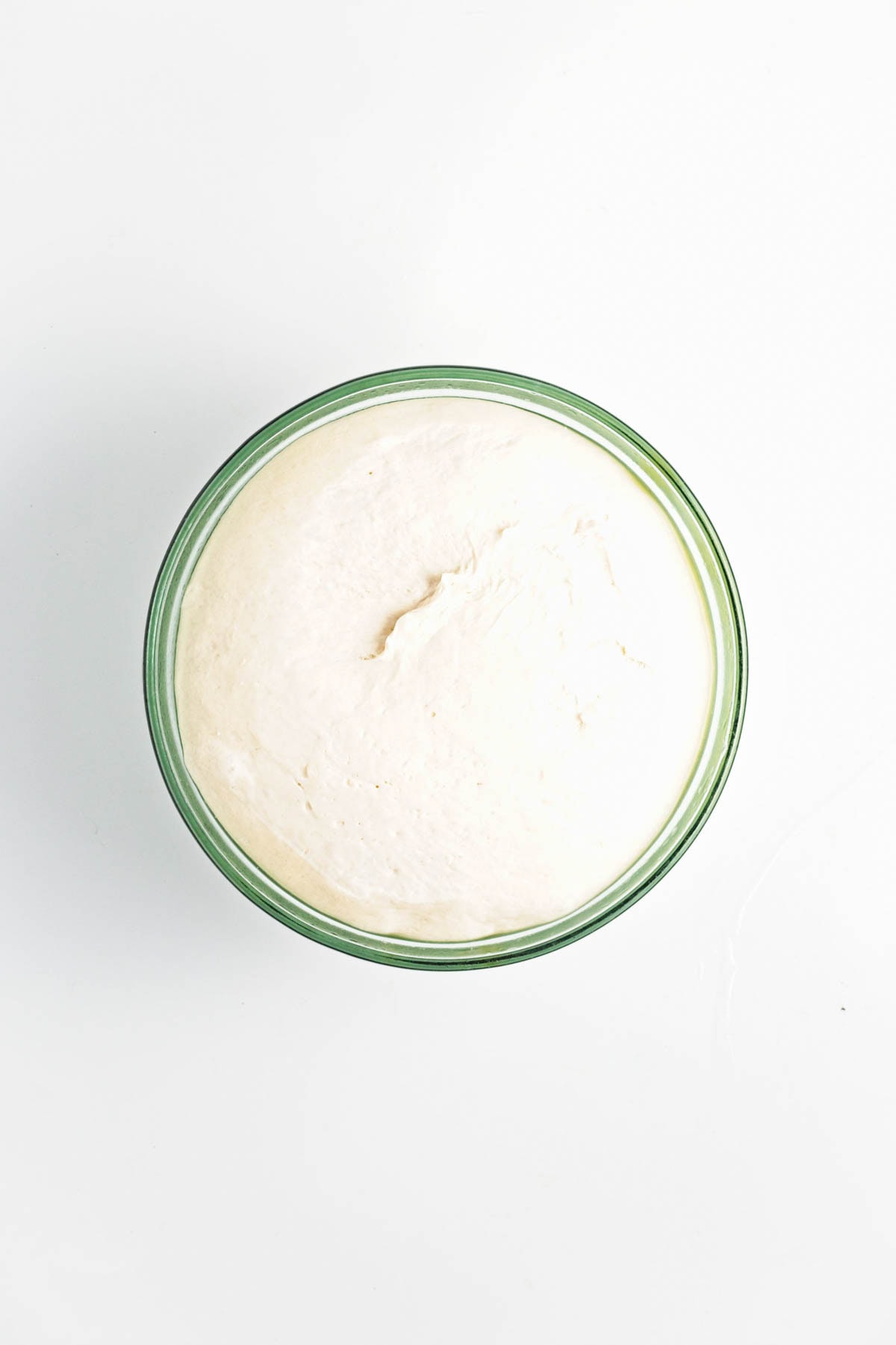 Risen dough in a glass bowl.