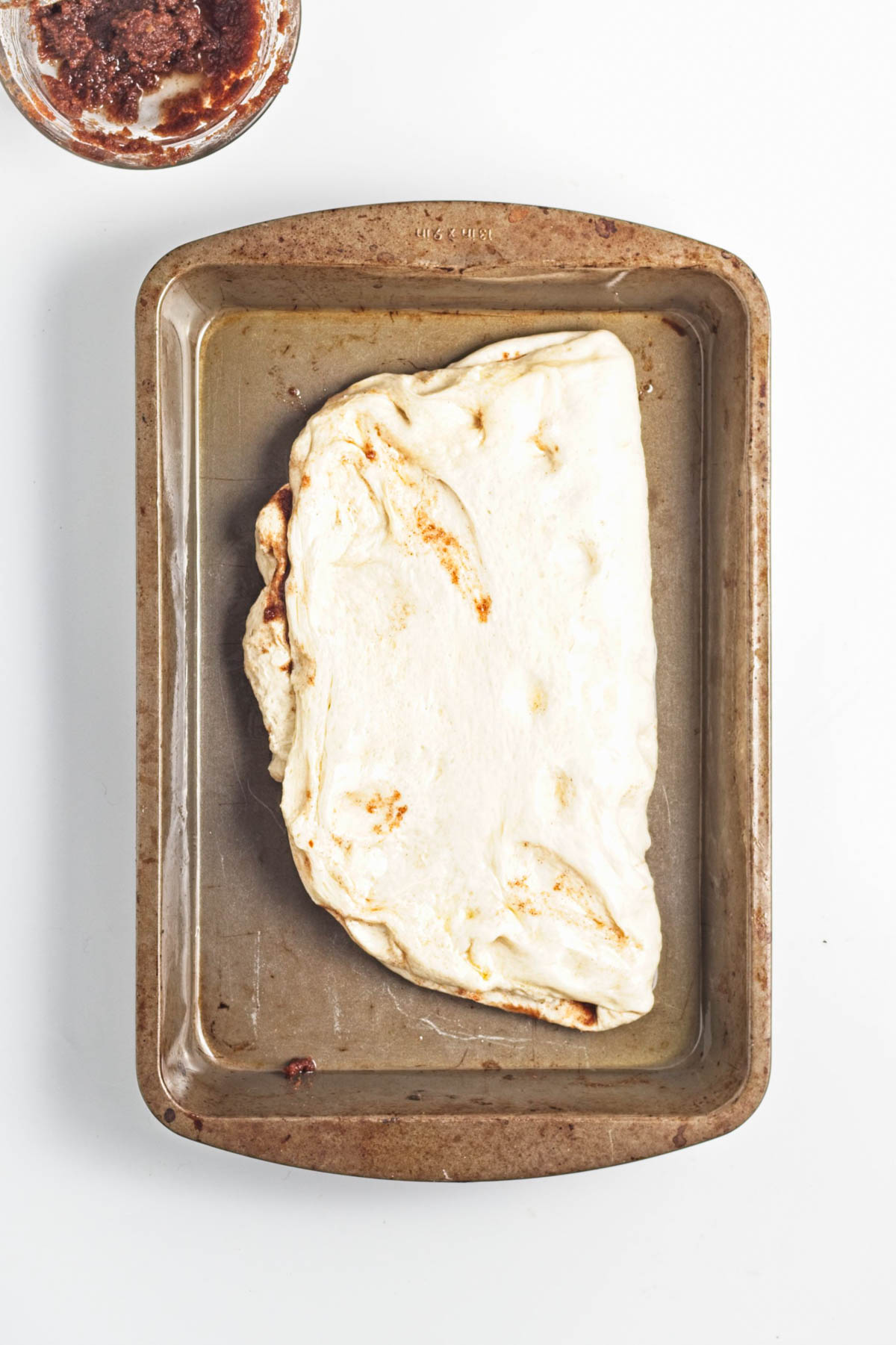 Dough folded over in a baking pan.