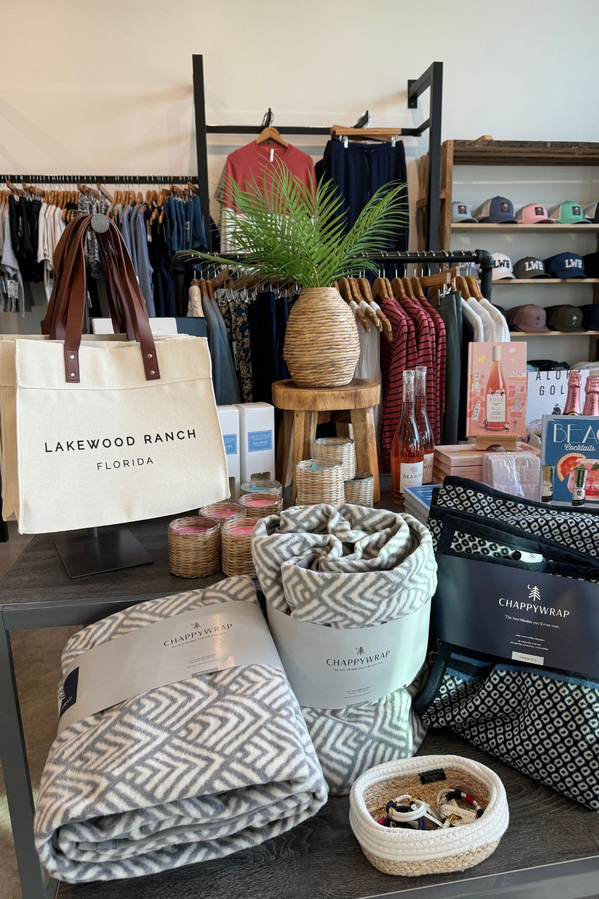 Retail store with wraps and tote bags in front and clothing and hats in the background.