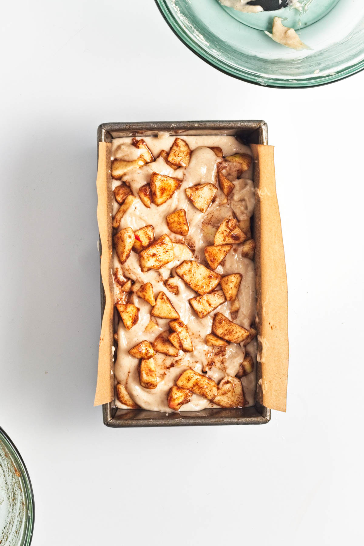 Batter in loaf pan with apples over top.