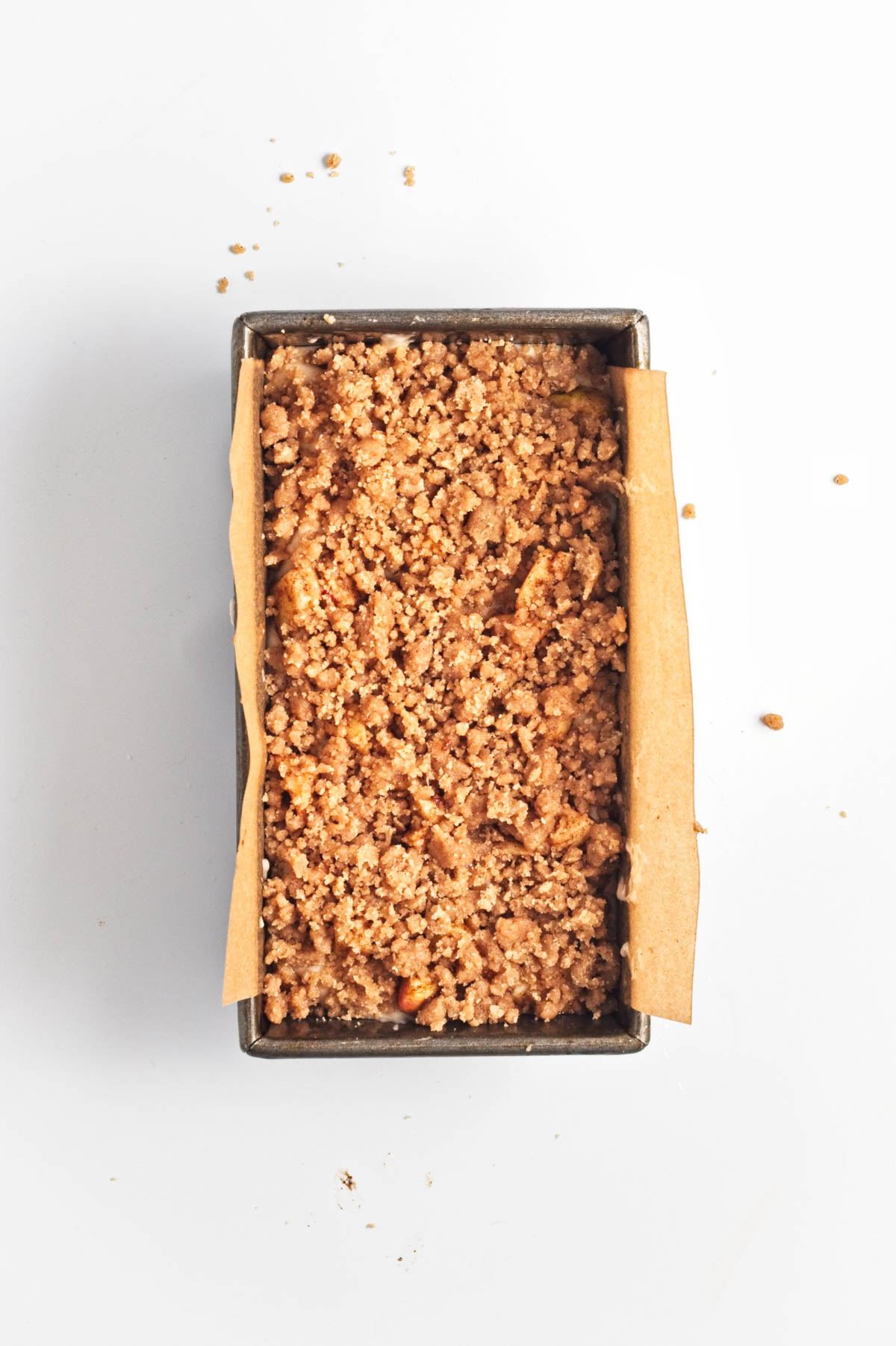 Loaf of baked apple cake in a pan with parchment paper.