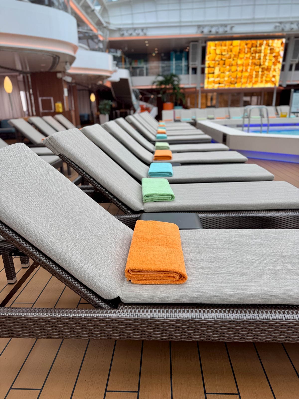 Row of pool loungers with multi-colored towels.