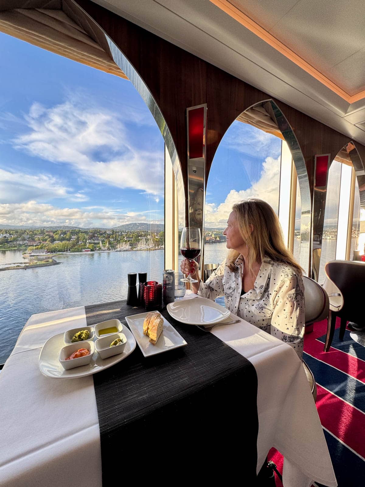 Woman sitting next to a window on a cruise ship at dinner.