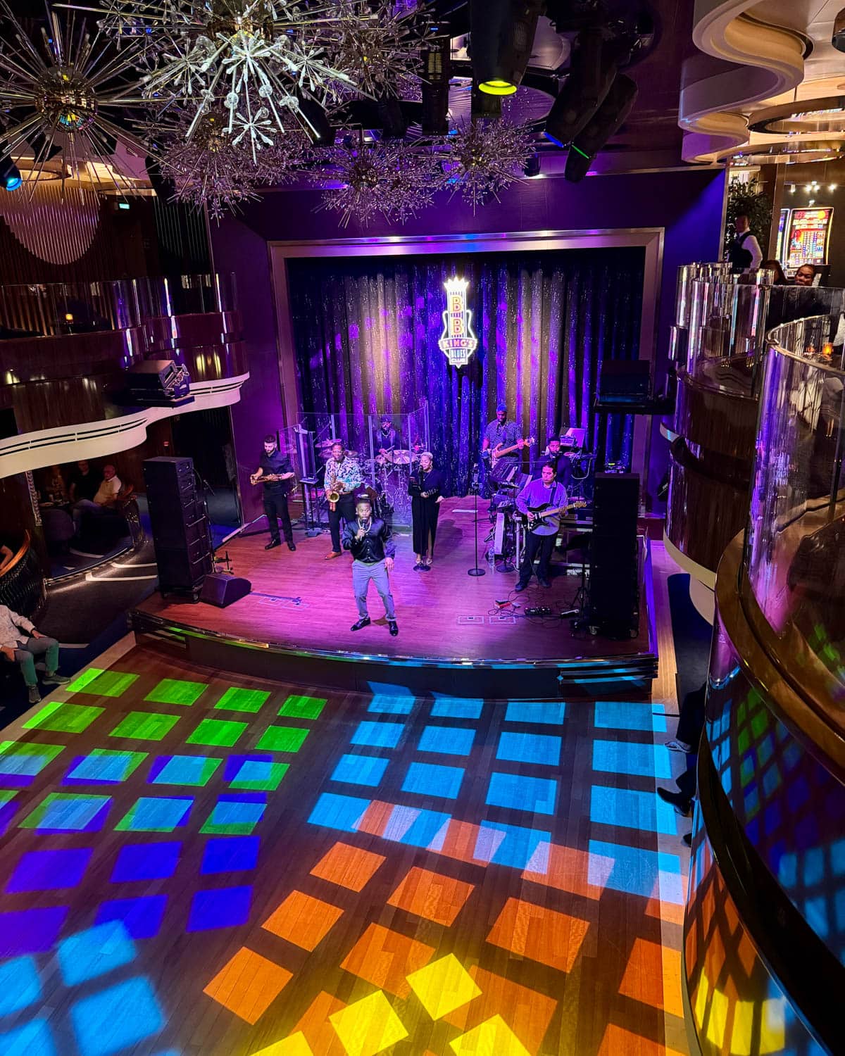 Band playing on a stage with multi-colored lights.