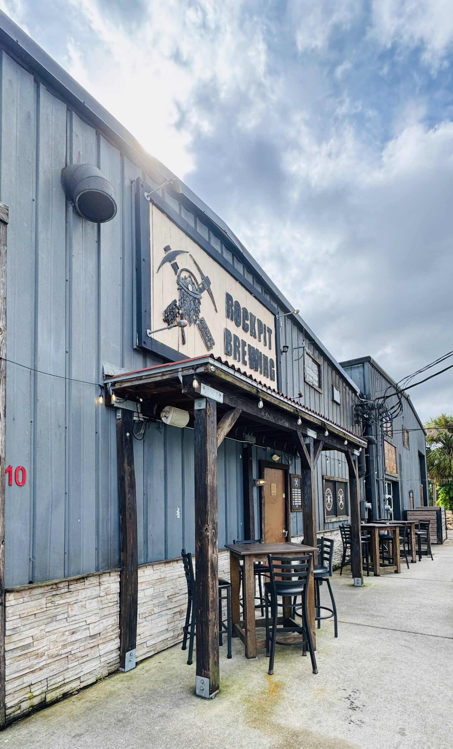Front of a brewery with tables and chairs outside.