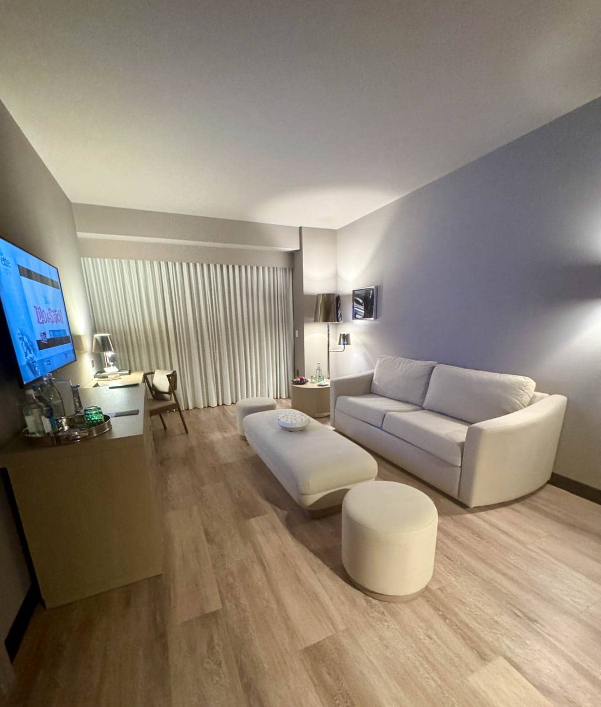 Living room with couch, tables, and console with TV on wall.