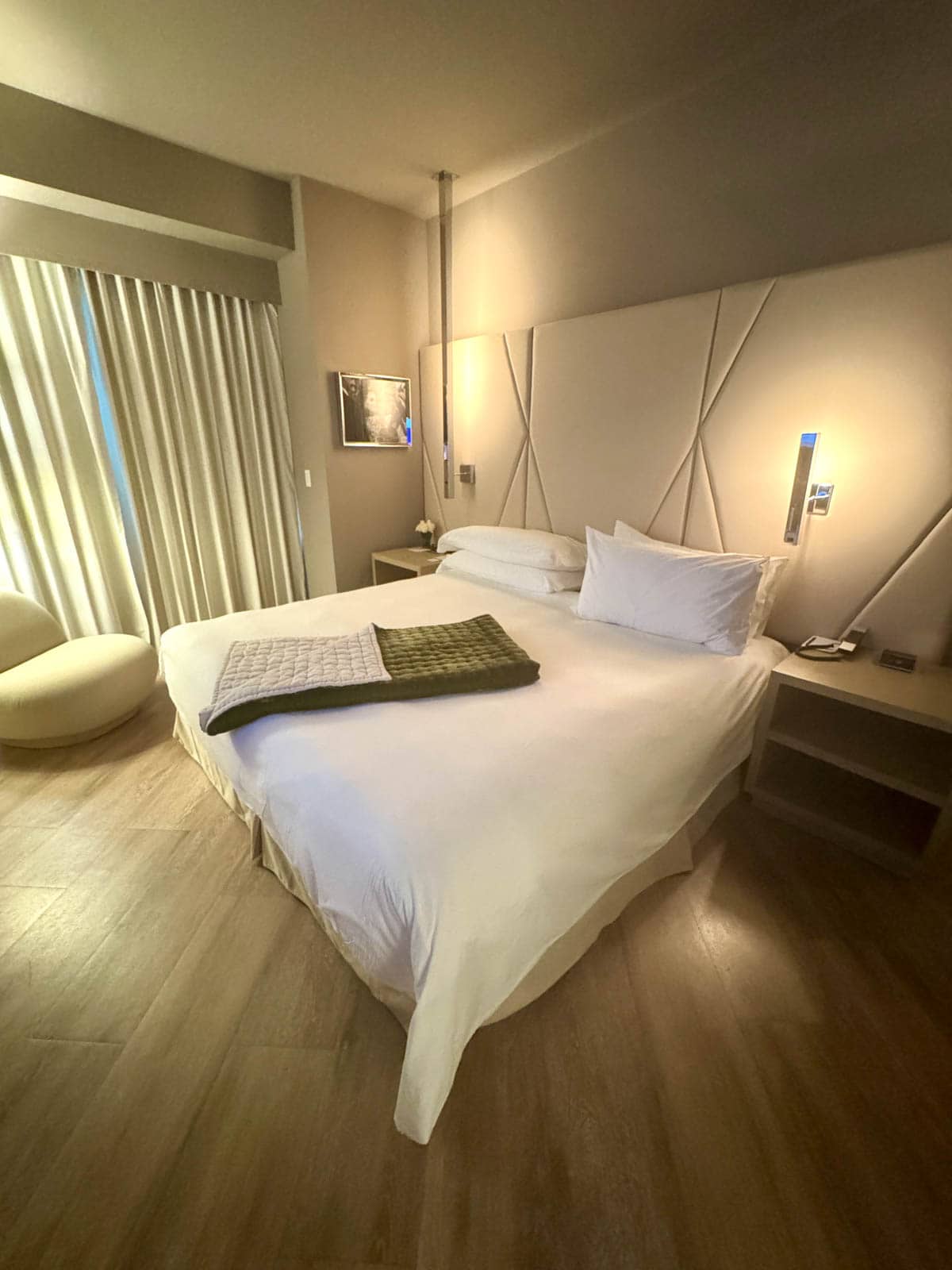 Bed in a hotel room with a throw over the comforter.