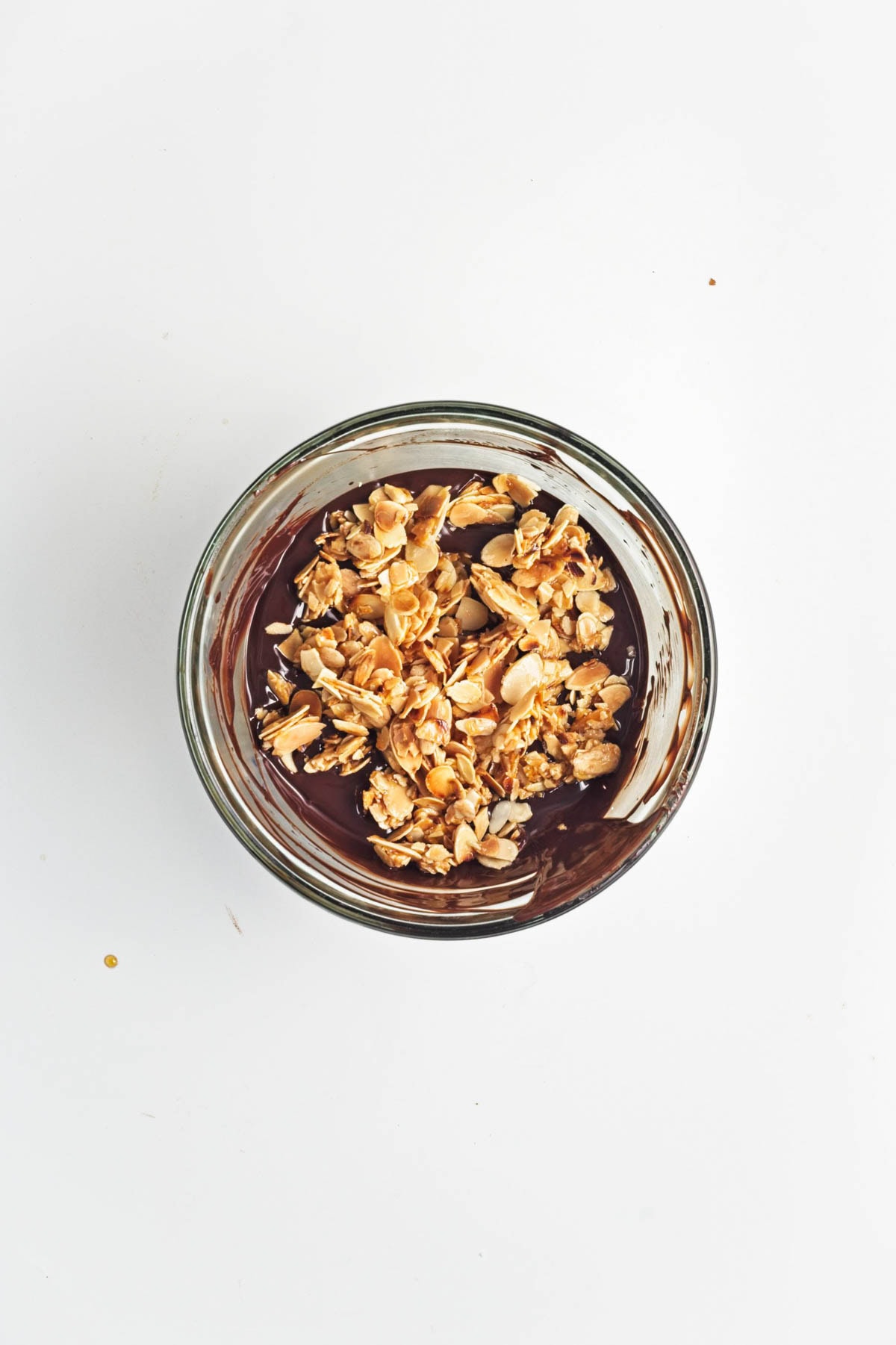 Melted chocolate with almonds on top in a glass bowl.