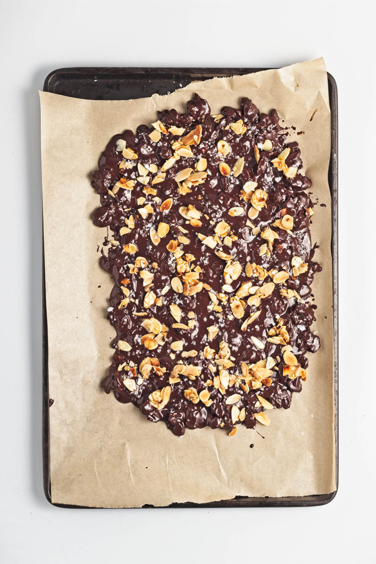 Dark chocolate almond bark on a parchment-lined baking sheet.