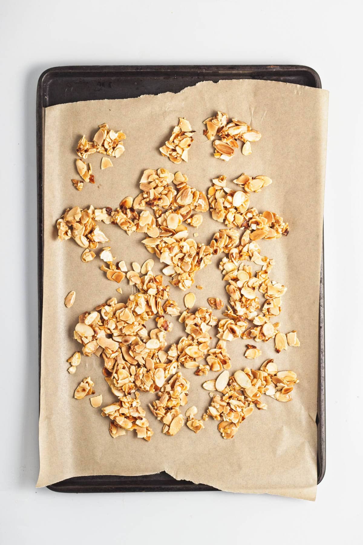 Candied almonds on a parchment-lined baking sheet.