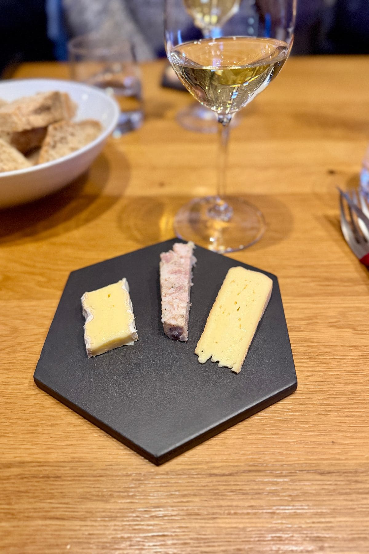 Cheese and meat tasting with a glass of white wine in the background.