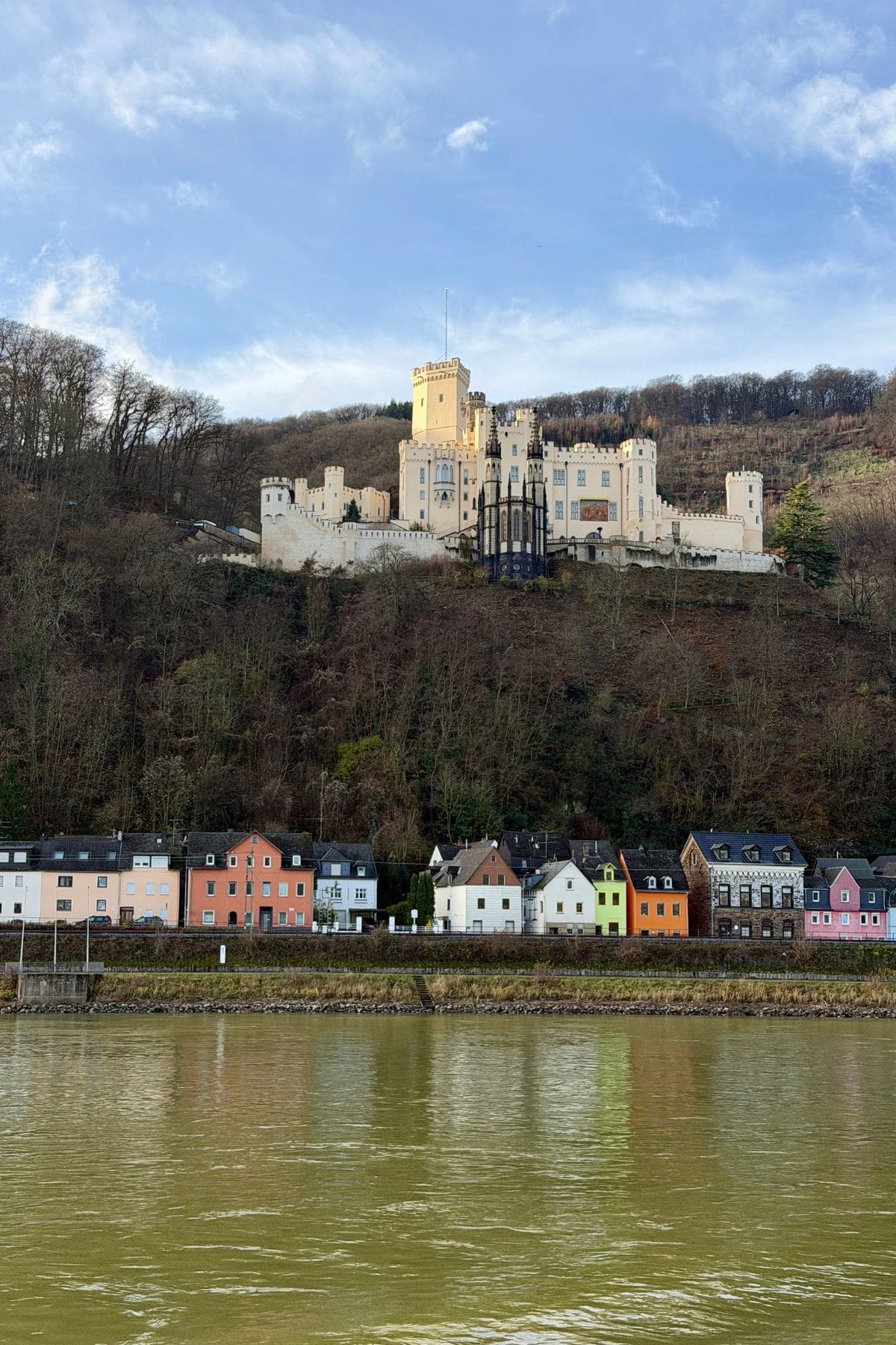 White castle on a hillside above colorful houses.